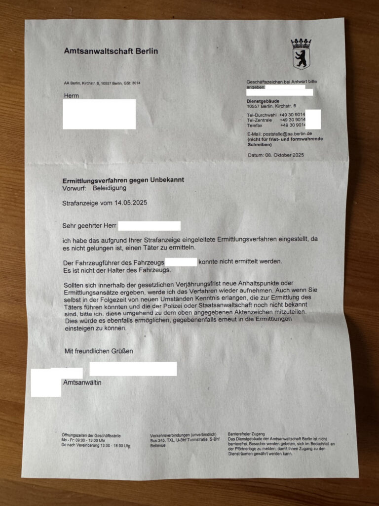 Das Bild zeigt ein Schreiben der Amtsanwaltschaft Berlin. Es handelt sich um die Mitteilung, dass ein Ermittlungsverfahren gegen Unbekannt wegen Beleidigung eingestellt wurde, da es nicht gelungen ist, einen Täter zu ermitteln. Der Fahrzeughalter konnte nicht ermittelt werden. Der Brief enthält den Hinweis, dass das Verfahren wieder aufgenommen werden kann, wenn sich innerhalb der Verjährungsfrist neue Anhaltspunkte ergeben. Er enthält außerdem Kontaktinformationen und Öffnungszeiten der Amtsanwaltschaft.
